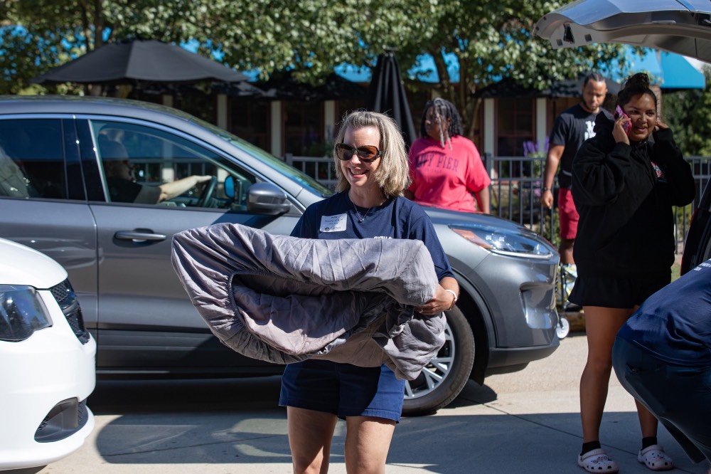 GVSU Alumna smiles while carries in luggage